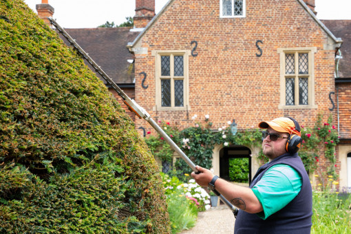 Garden maintenance operative trimming and shaping hedge