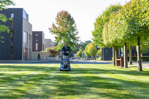 Grounds maintenance operative mowing lawn