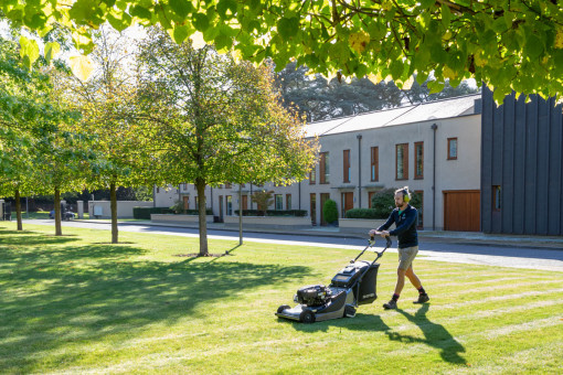 Grounds maintenance operative mowing lawn in well maintained grounds.
