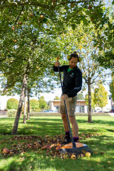 Grounds maintenance operative raking fallen leaves