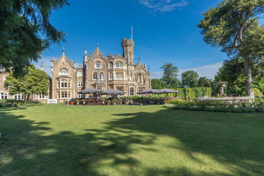 Mown lawn leading to outdoor dining area at Oakley Court Hotel