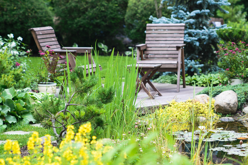 Wooden chairs next to garden pond